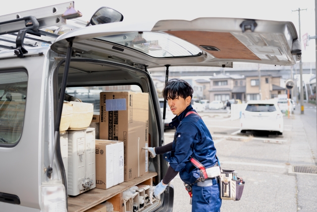 作業車からエアコンを取り出す電気工事士
