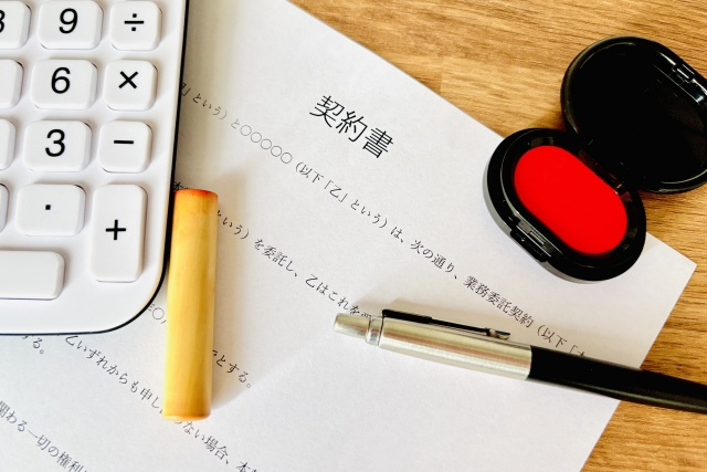 契約書と印鑑、電卓、ペンが並ぶ契約手続きのイメージ
